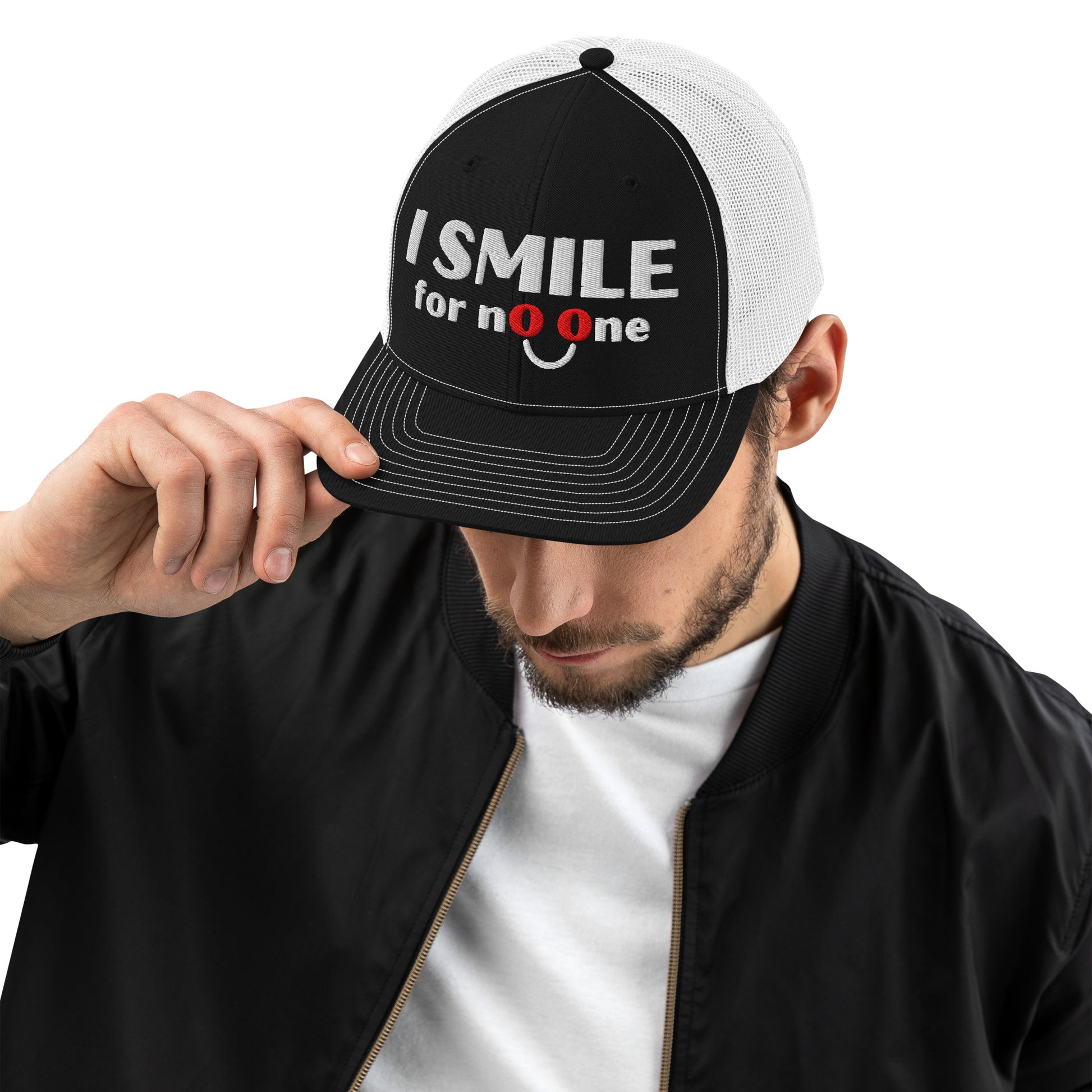Man in a black and white trucker hat with embroidered text 'I Smile for No One' in bold white lettering. Structured cap with mesh back and adjustable snapback.