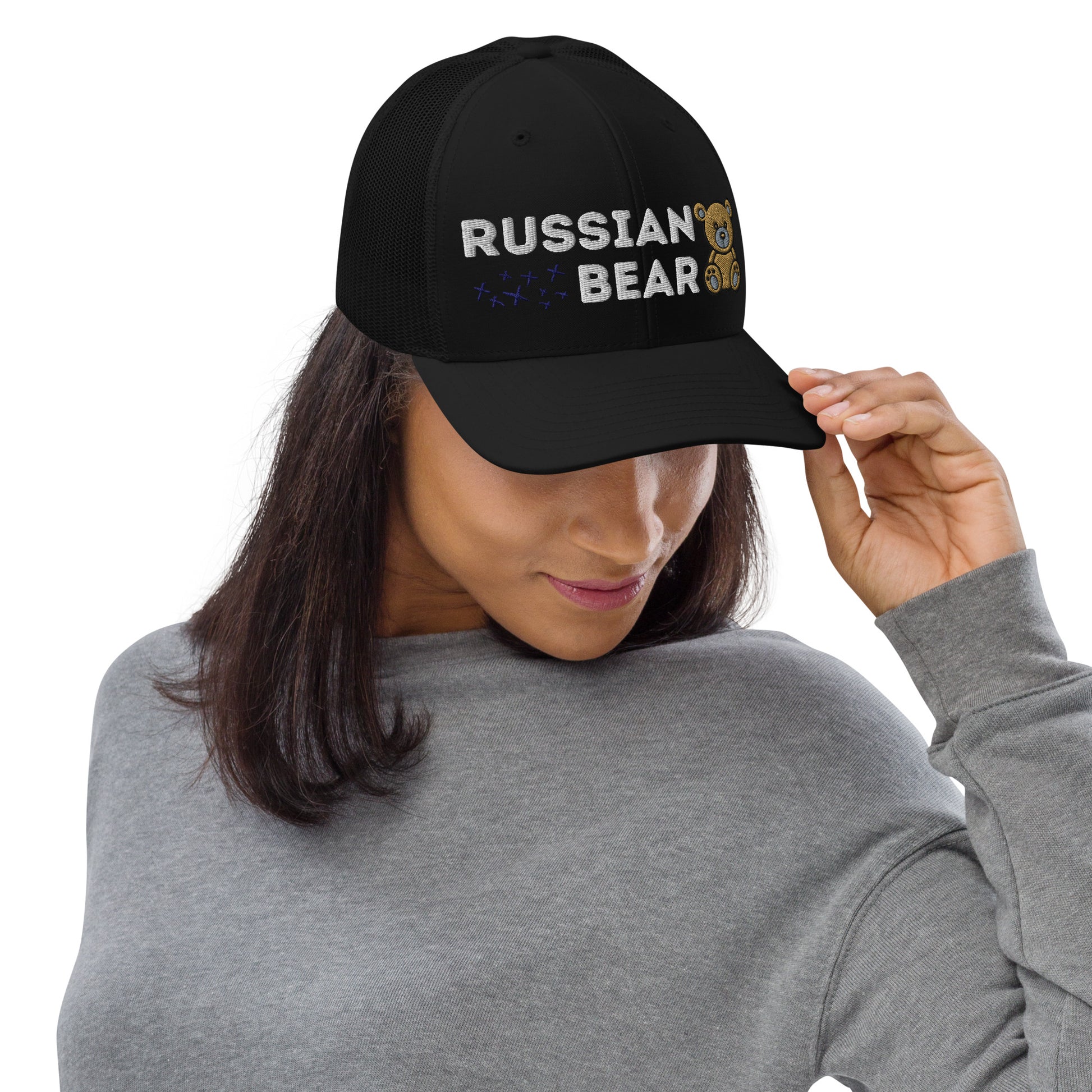 Black trucker hat with embroidered 'RUSSIAN BEAR' text and cute bear design, on a woman.