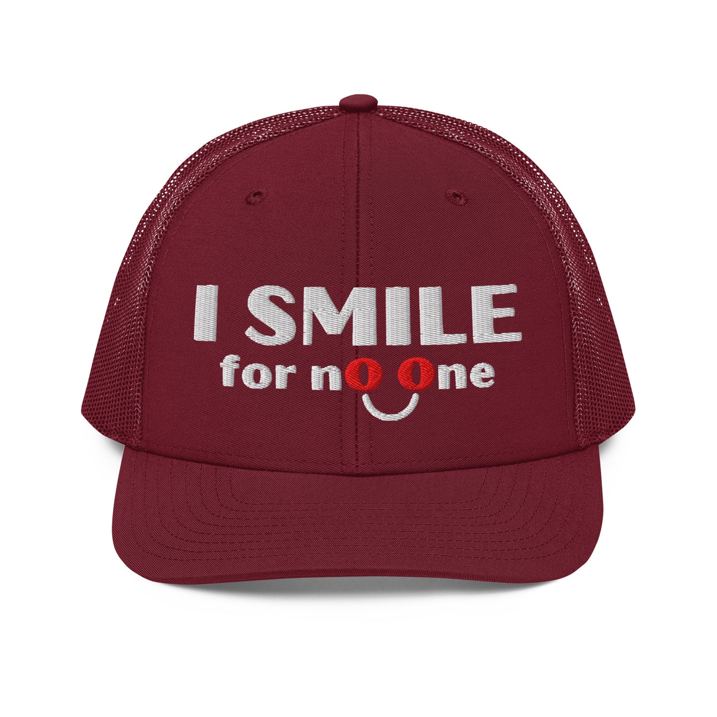 Red cardinal trucker hat with embroidered text 'I Smile for No One' in bold white lettering. Structured cap with mesh back and adjustable snapback.