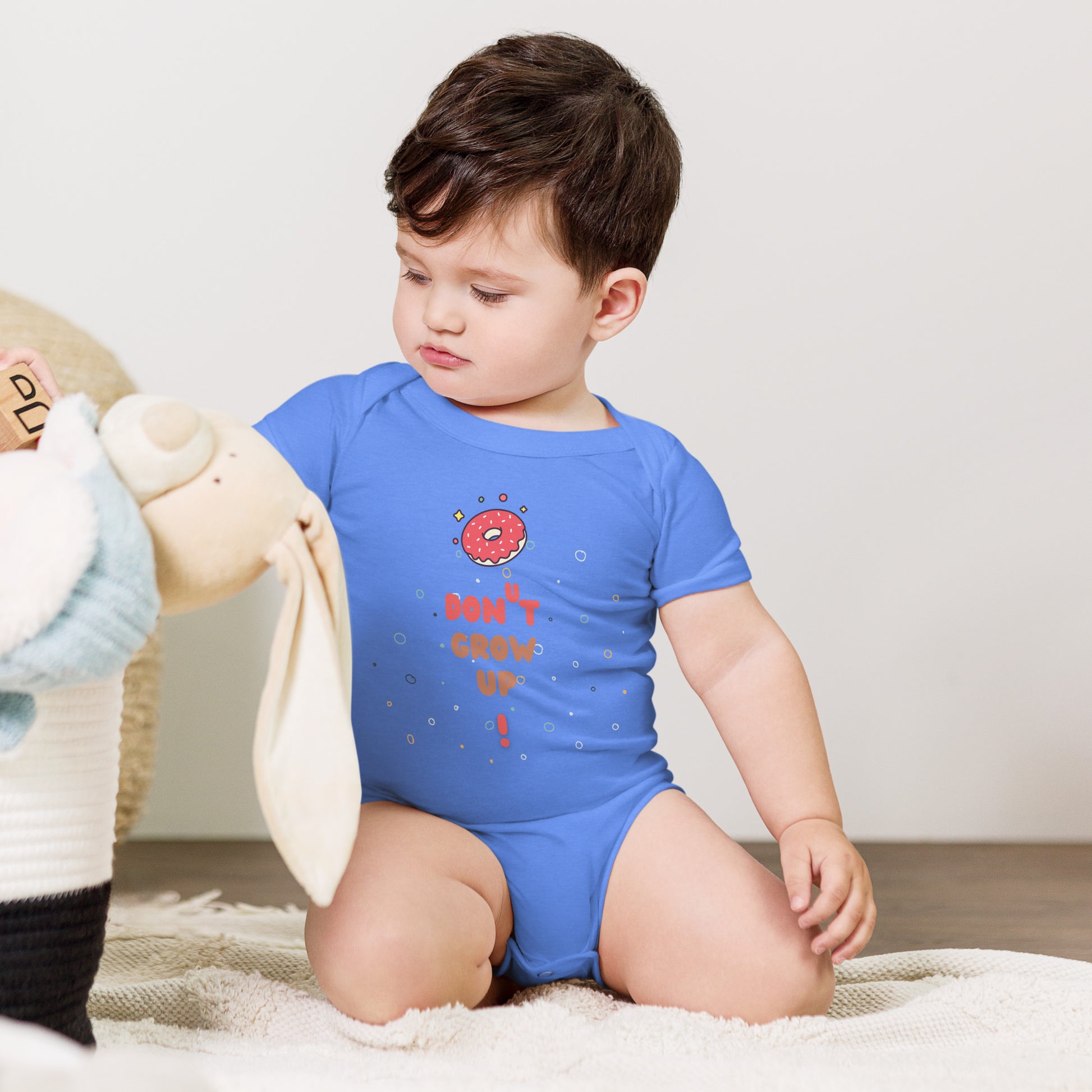 Baby in a blue onesie with "Don't Grow Up!" with donut caption.