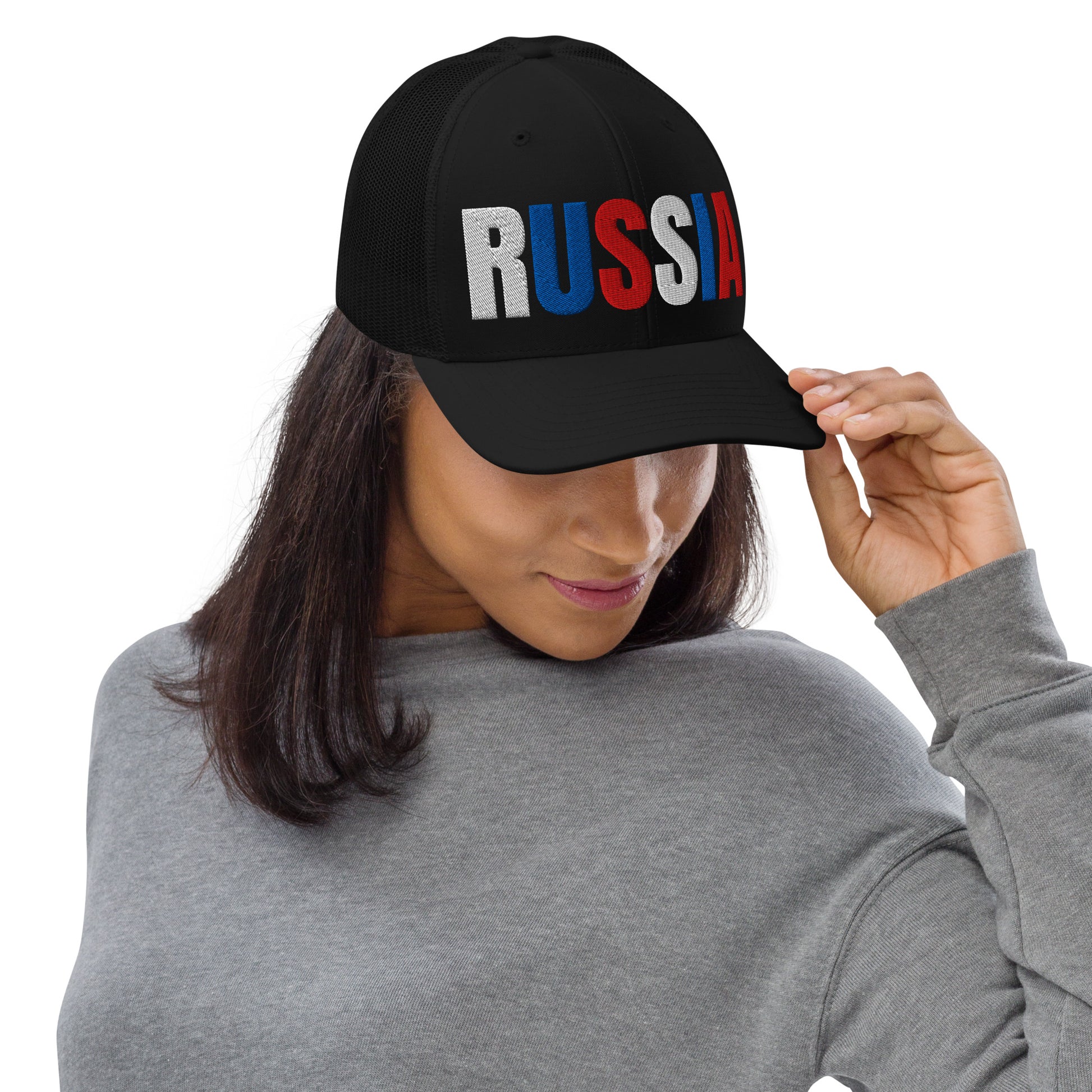 Woman wearing a black embroidered 'RUSSIA' trucker hat with Russian flag colors. Classic design featuring a cotton blend front, mesh back, and adjustable snapback for a comfortable, stylish fit.