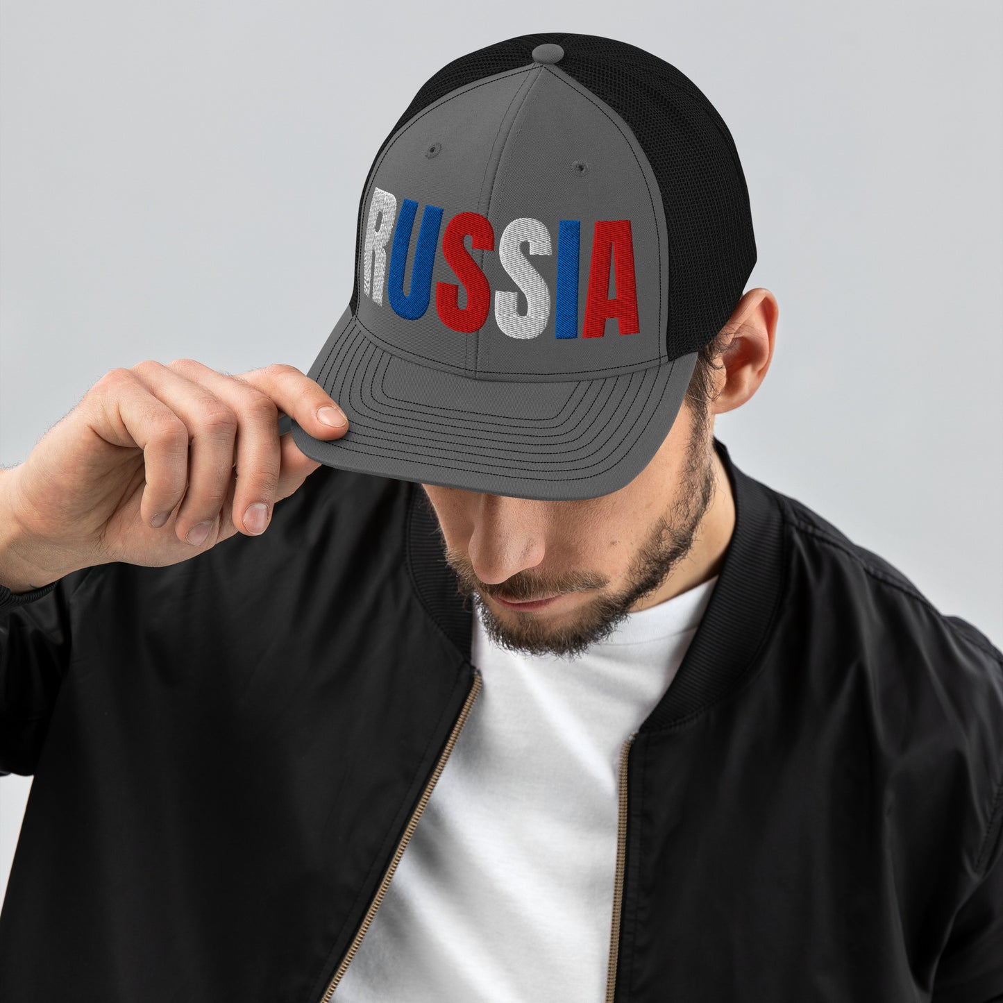 Man wearing a grey embroidered 'RUSSIA' trucker hat with Russian flag colors. Classic design featuring a cotton blend front, mesh back, and adjustable snapback for a comfortable, stylish fit.