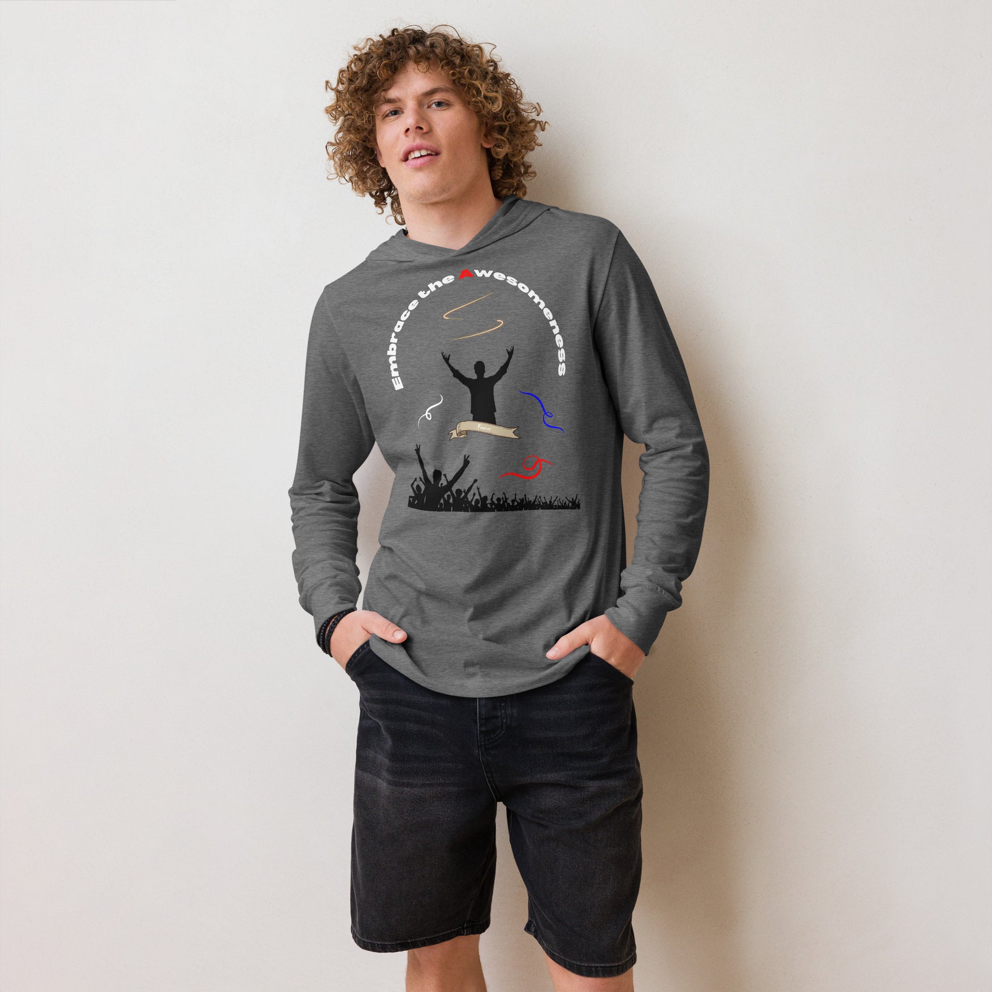 man in long sleeve heather grey hoodie with words embrace the awesomeness inscribed in a half circle around a man with arms raised up you see whate blue and red colors featured and a crowd of people cheering in the background from the bottom