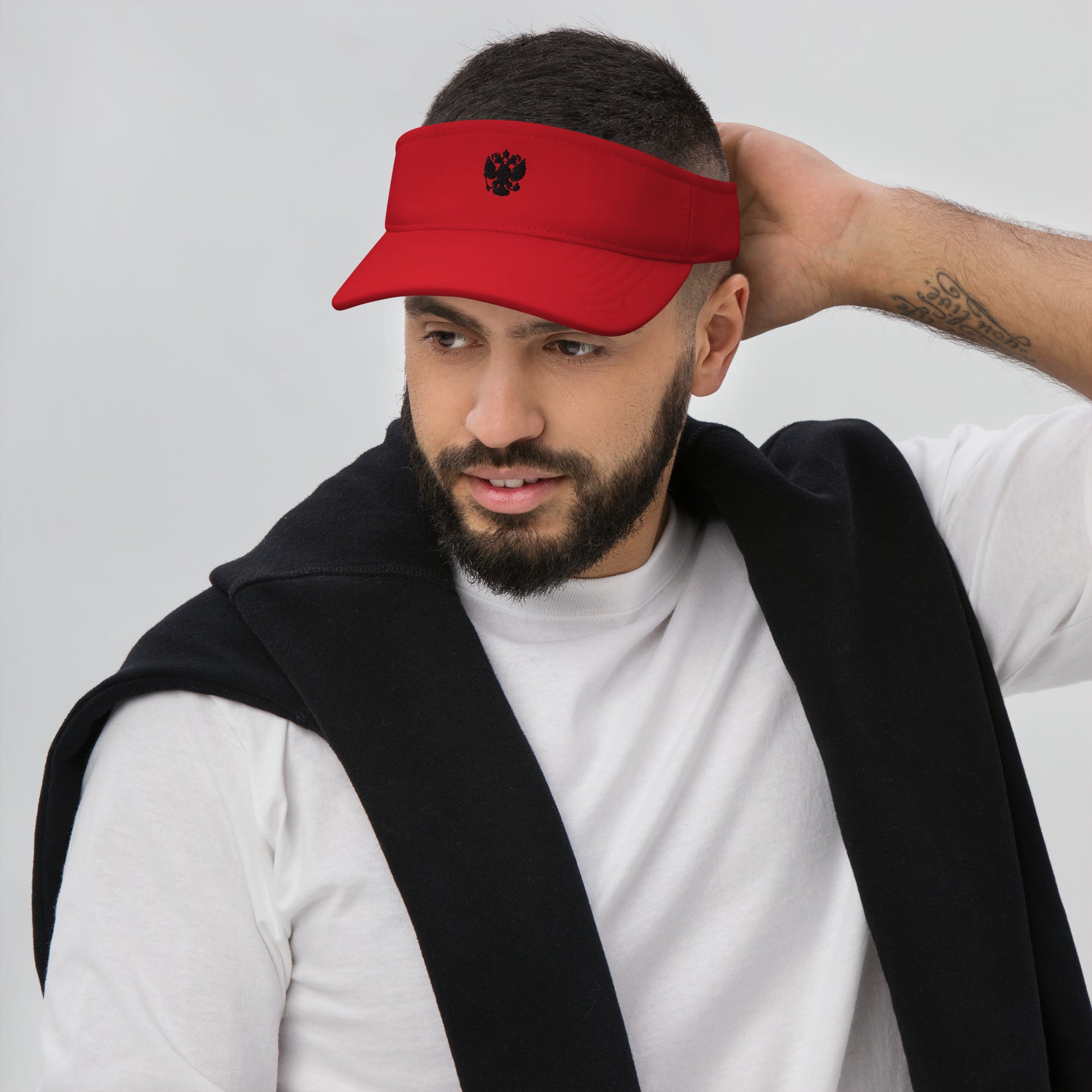 man in red visor with black russian coat of arms embroidered on the front