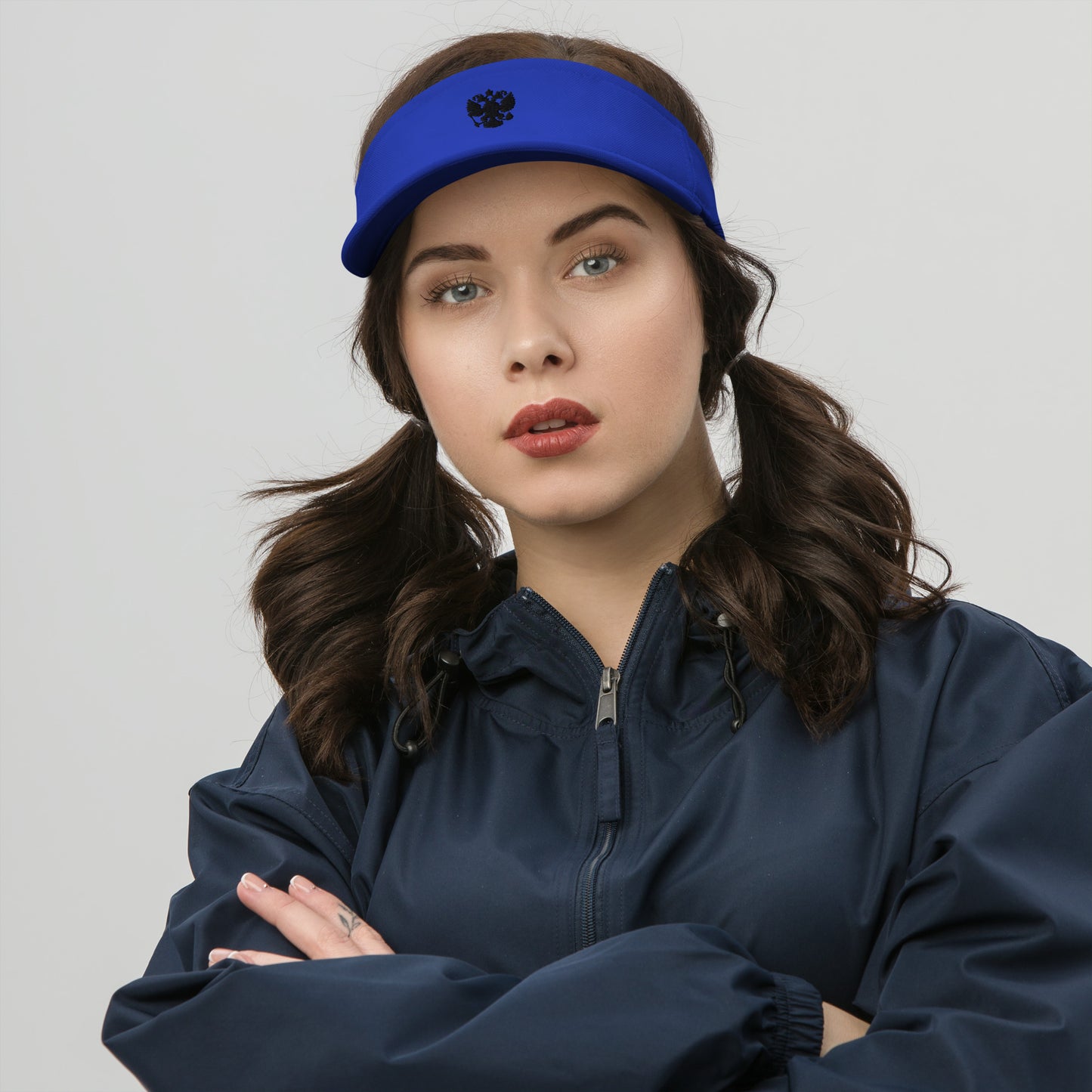 woman in royal blue visor with black russian coat of arms embroidered on the front